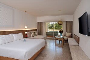 A modern hotel room with a large bed, a seating area with a table, and a TV mounted on the wall. - Kimpton Tres Rios All Inclusive by IHG (Playa del Carmen)