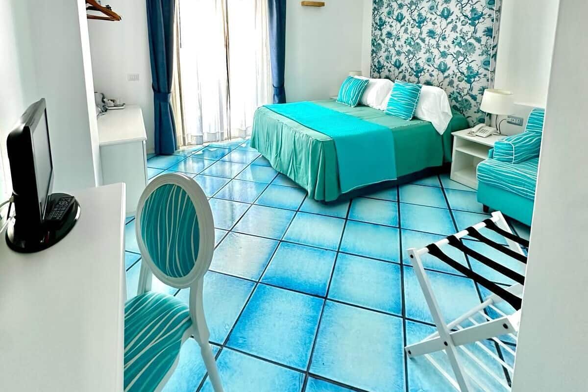 A room with a bed, a desk, a chair, and a small table.