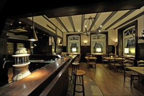 A bar area with a long counter, stools, and hanging lights. - Best Western Hotel Lippstadt (Lippstadt)
