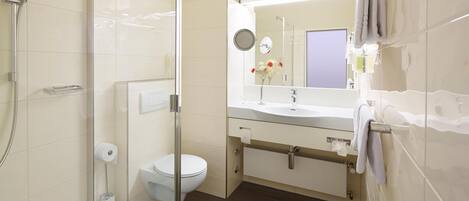 A modern bathroom with a glass shower enclosure, a toilet, a sink with a mirror, and a towel rack.