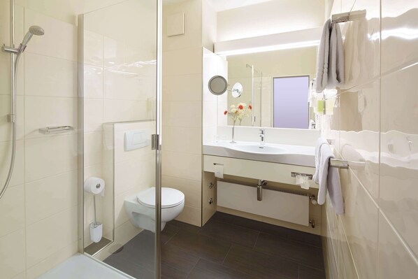 A modern bathroom with a glass shower enclosure, a toilet, a sink with a mirror, and a towel rack. - Best Western Hotel Lippstadt (Lippstadt)