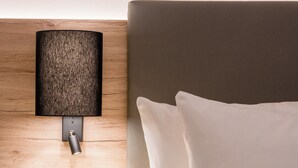 A modern hotel room with a wooden headboard, a wall-mounted lamp, a bedside table, and a power outlet. - Best Western Hotel Lippstadt (Lippstadt)