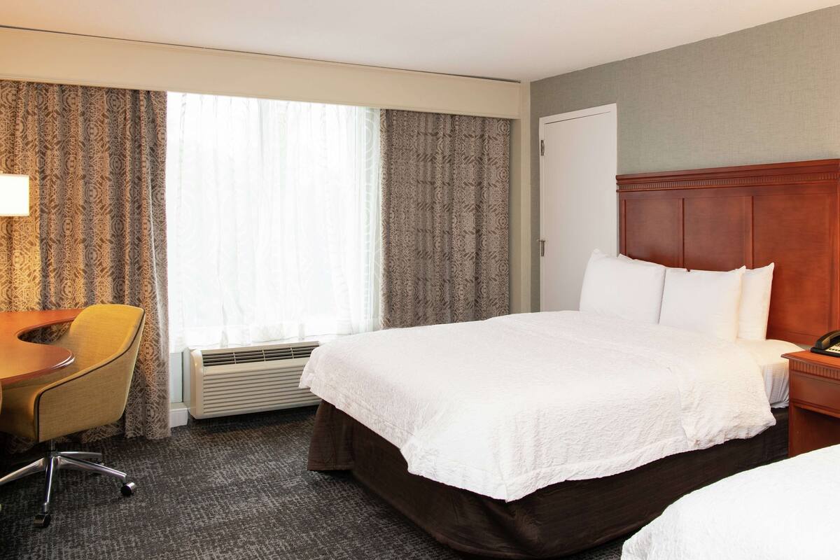 A hotel room with a bed, a desk, and a chair.