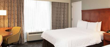 A hotel room with a bed, a desk, and a chair.