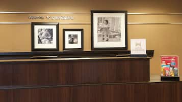 A reception desk with framed photographs, a 'Welcome to Parsippany' sign, and a Hilton Honors sign.