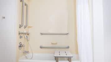 A bathroom with a bathtub, grab bars, and a shower control panel.