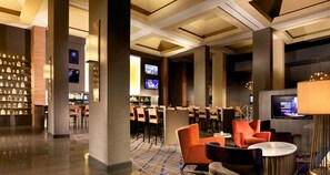 A modern hotel lobby with a bar area, seating, and a television screen. - Hampton Inn Parsippany (Parsippany)