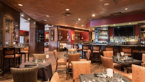 A restaurant with wooden flooring, wicker chairs, and tables set for dining.
