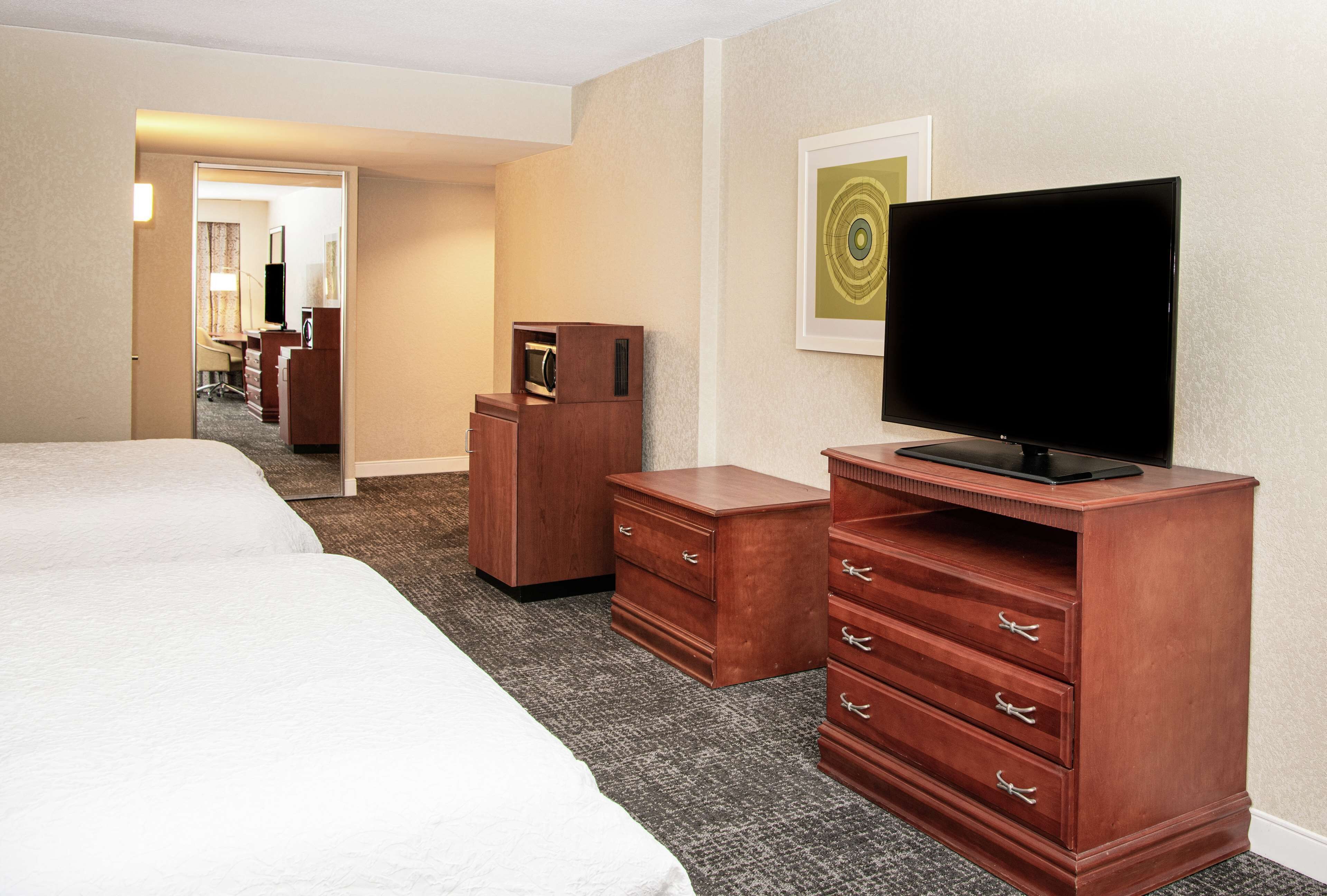 Een hotelkamer met twee bedden, een televisie, een houten dressoir en een bureau met lades.