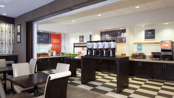 Enjoy a warm and inviting café experience with comfortable seating, a variety of tables, and a coffee station.