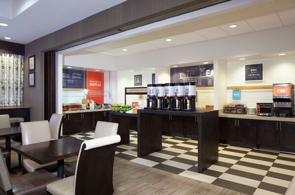 A modern cafe with checkered flooring, a coffee bar, and seating areas.