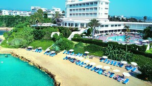 Um resort com praia, área de piscina e um edifício grande com várias varandas.