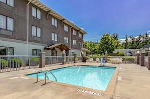 Relax by the pool surrounded by lush greenery and comfortable lounge chairs.