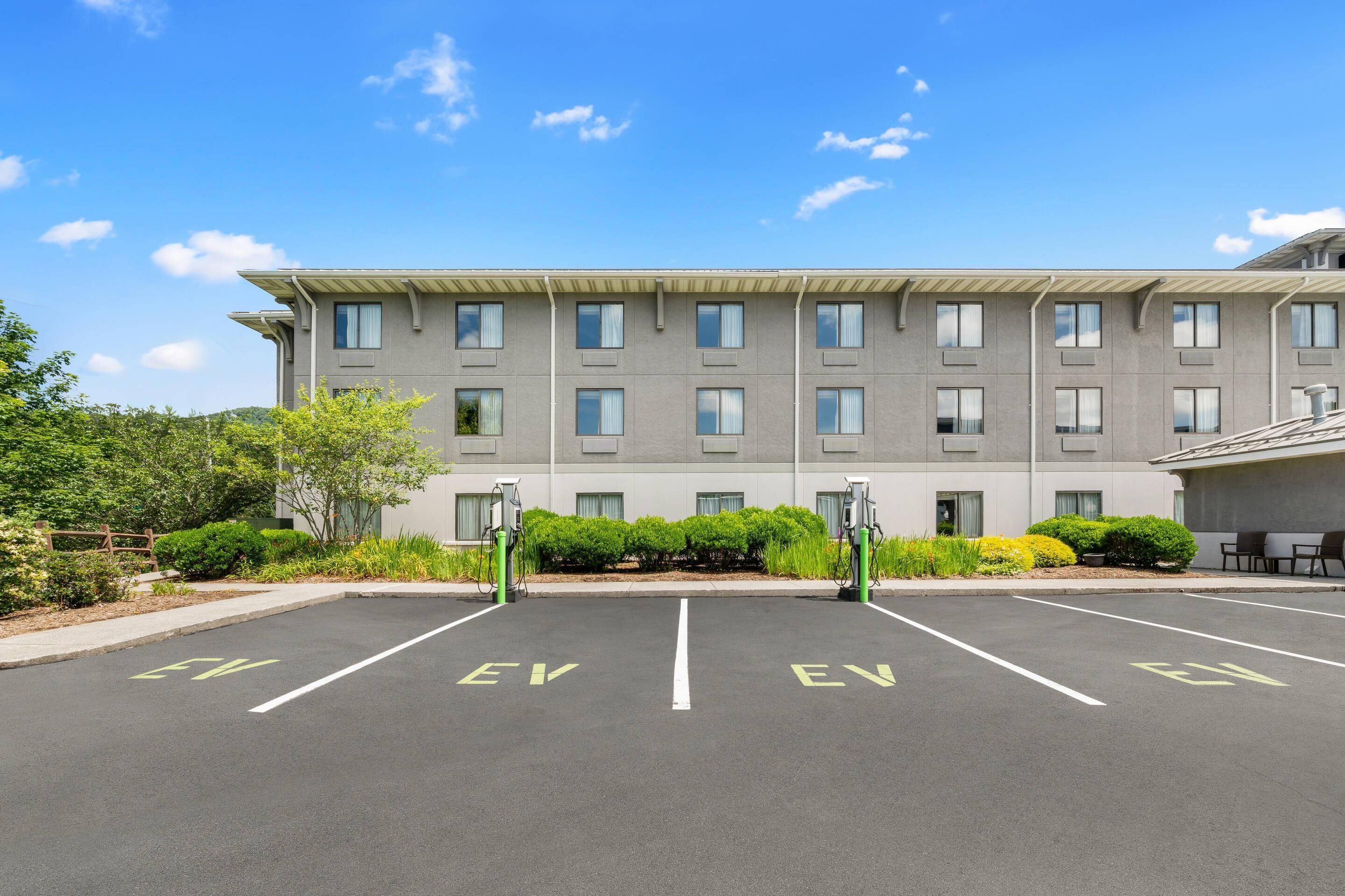 A parking lot with EV charging stations and a building with multiple windows and a flat roof.