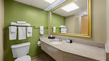 A bathroom with a green wall, white toilet, and a sink with a mirror.
