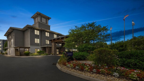 A modern hotel with a stone facade, a covered entrance, and a landscaped garden with a sign indicating the entrance. - Sleep Inn Boone University Area (Boone)