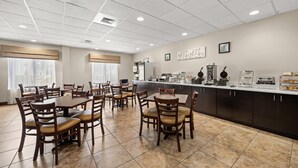 A hotel dining area with multiple tables and chairs, a kitchen counter with appliances, and a tiled floor. - Sleep Inn Boone University Area (Boone)