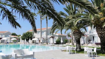 Una piscina al aire libre, sombrillas, sillones reclinables de piscina