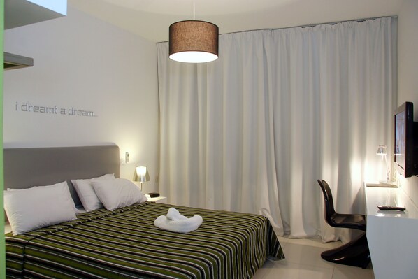 A hotel room with a bed, a chair, a desk, and a television.
