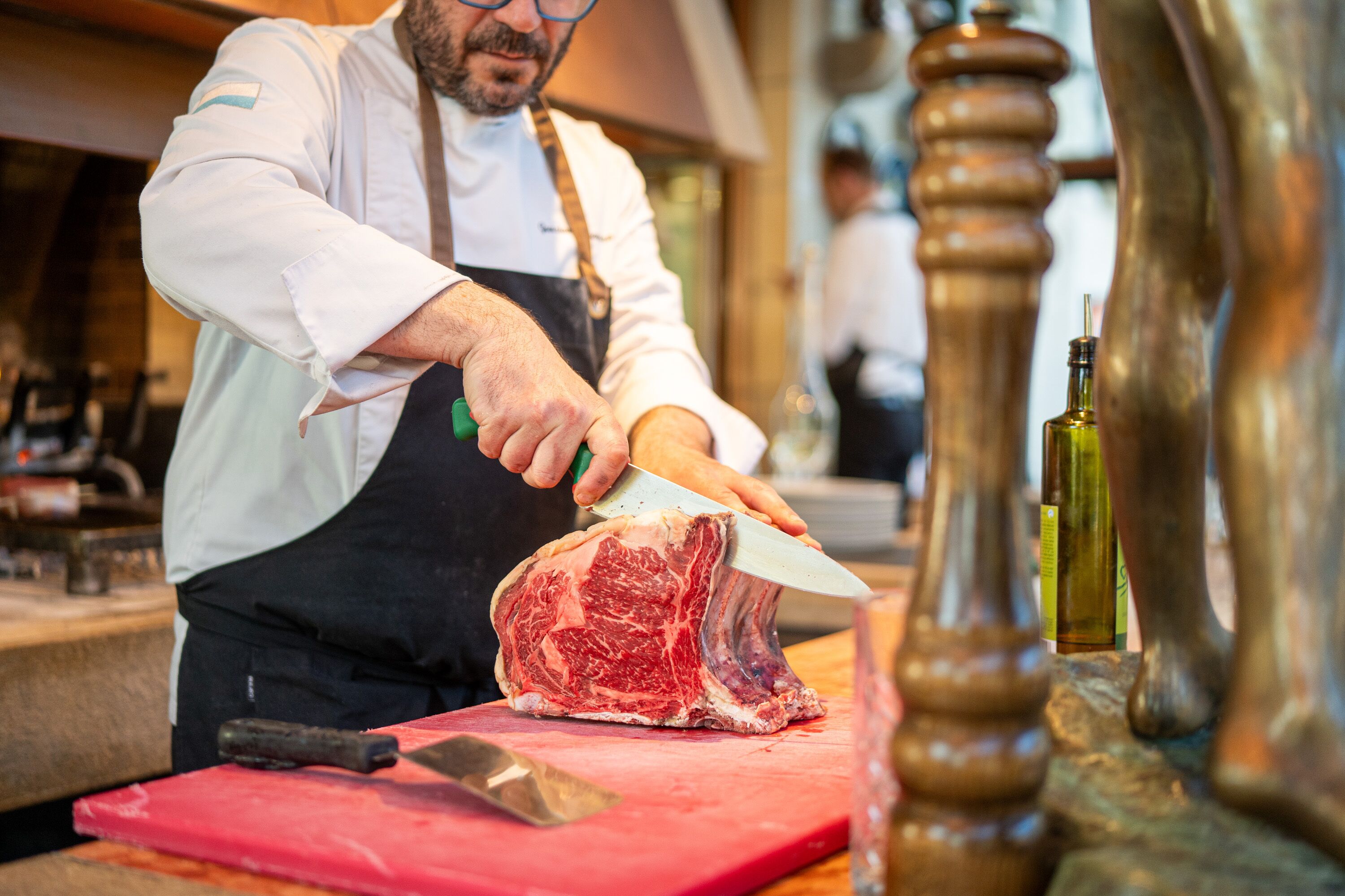 Une personne qui découpe de la viande sur une planche à découper rouge.