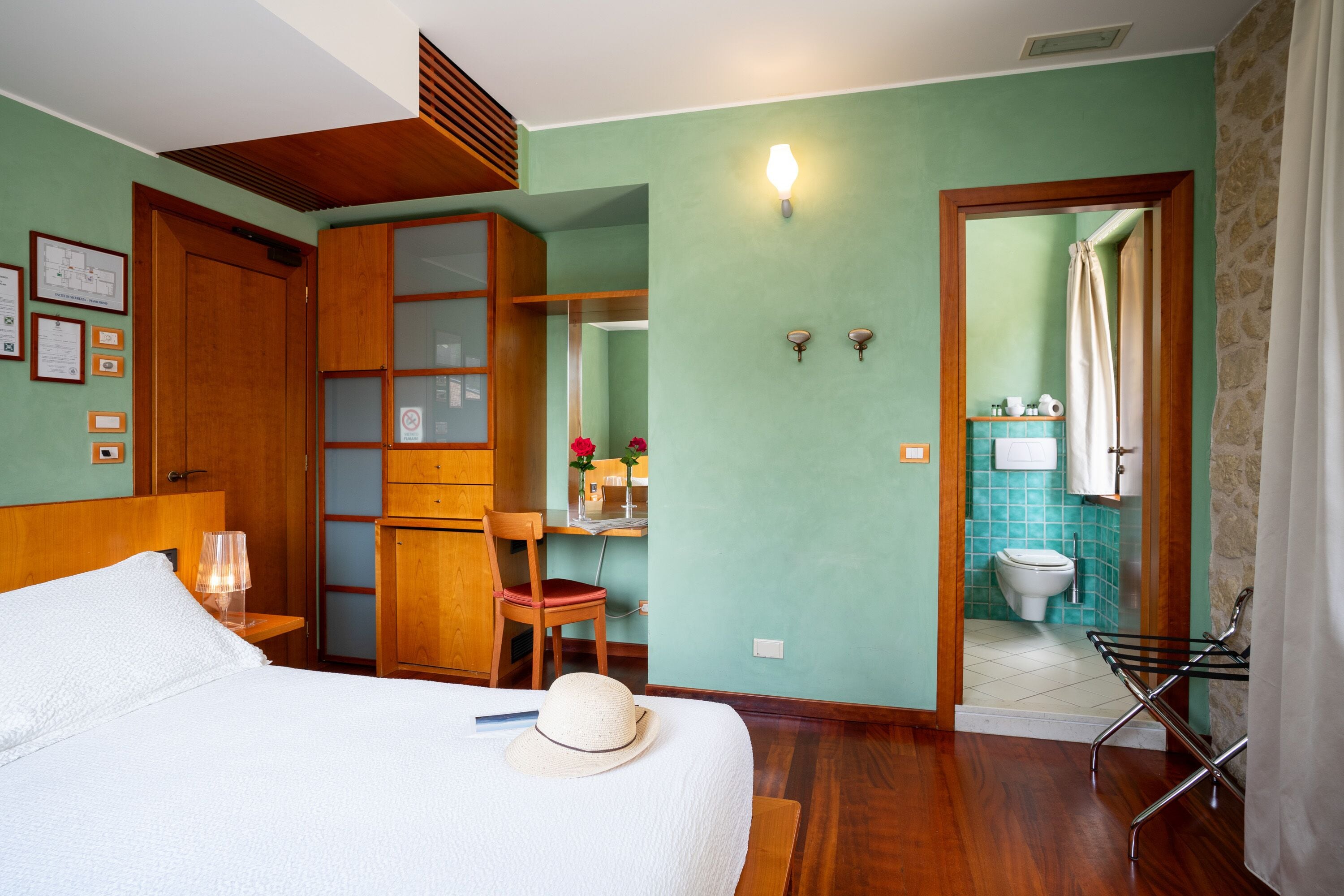 A hotel room with a bed, a desk, a chair, a bathroom with a toilet and sink, and a shower.