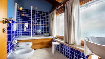 Un bagno con piastrelle blu, una vasca, un lavandino e una finestra con tende.