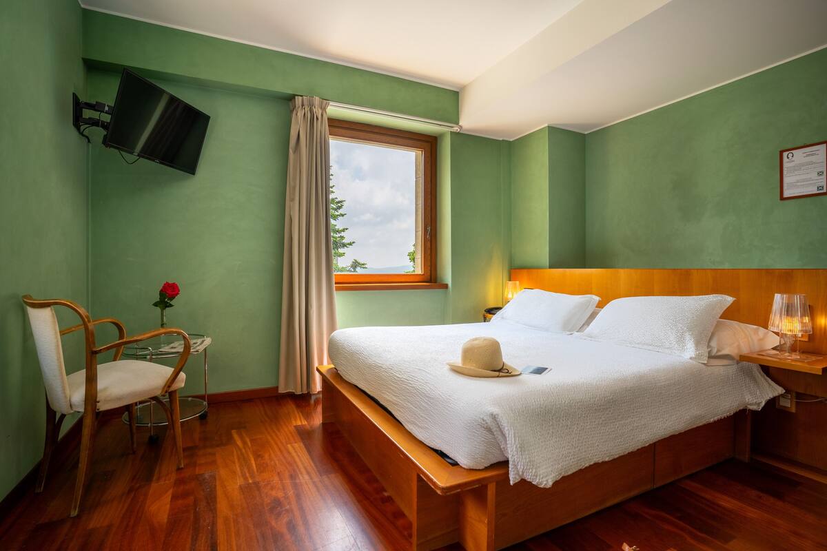 A neatly arranged bedroom with a bed, bedside table, lamp, and a chair.