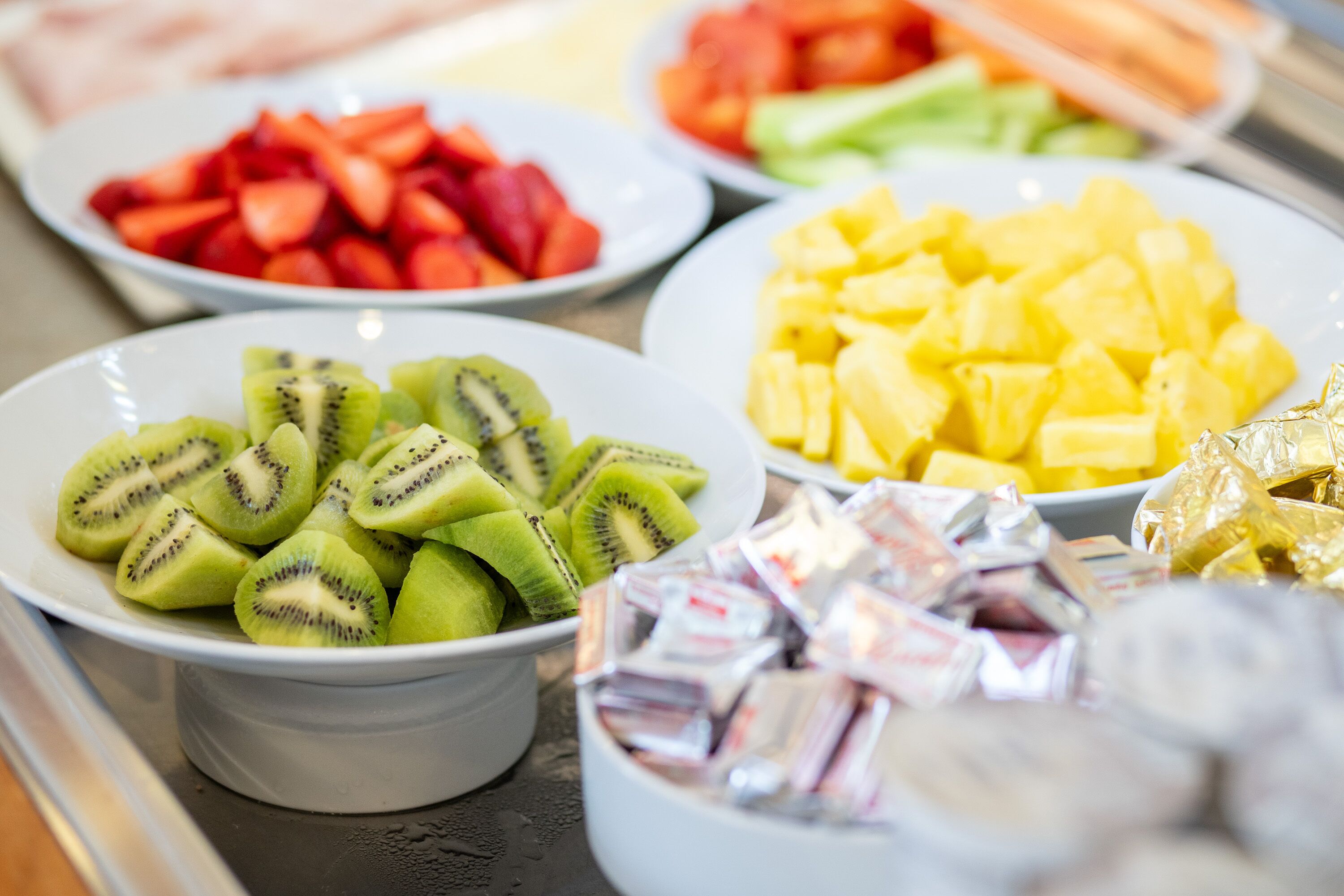 Un bufé con diversas frutas, incluyendo kiwi en rodajas, piña y sandía.