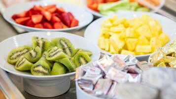 Un bufé con diversas frutas, incluyendo kiwi en rodajas, piña y sandía.