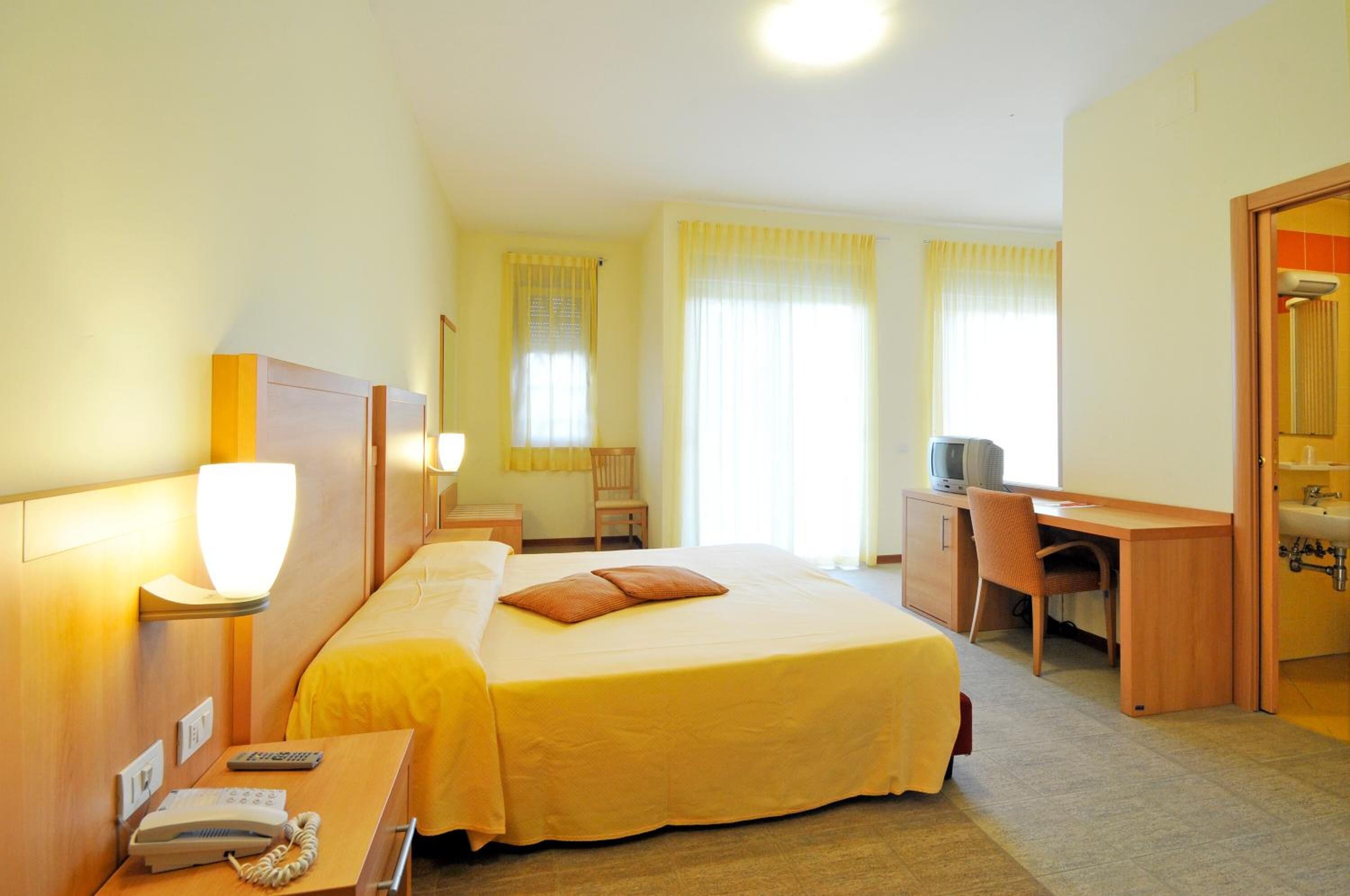 Habitación de hotel con cama, escritorio, silla y baño.