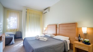 A hotel room with a large bed, a bedside table with a lamp, a small desk, and a chair. - Hotel Foresteria Volterra (Volterra)