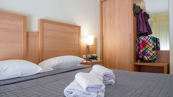 A hotel room with a bed, a nightstand, a mirror, and a wardrobe.