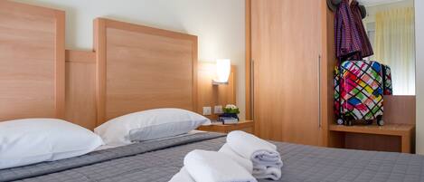 A hotel room with a bed, a nightstand, a mirror, and a wardrobe.