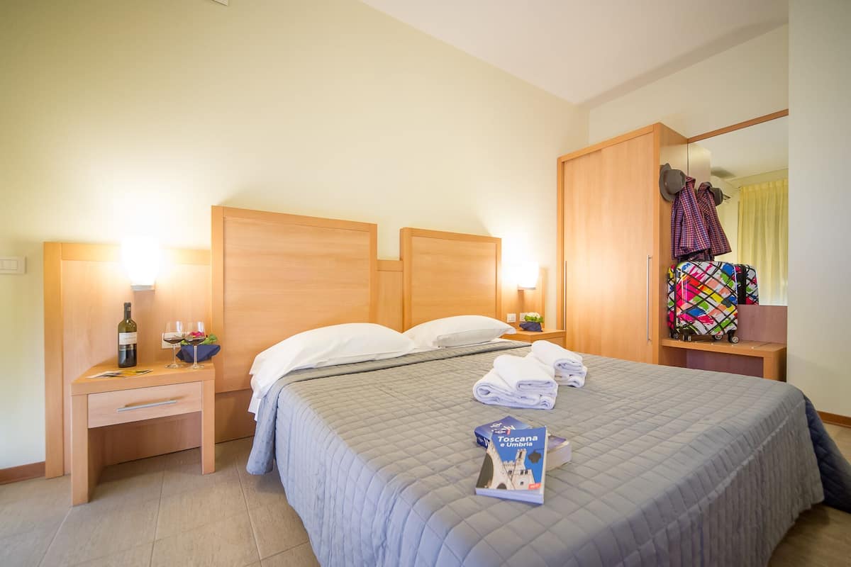 A hotel room with a bed, a nightstand, a wardrobe, and a suitcase.