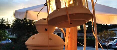 A lantern hanging from a pole, with a table and chairs below.