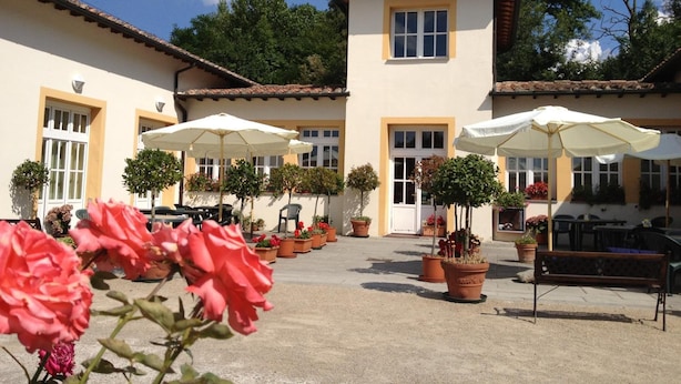 A courtyard with outdoor seating, potted plants, and a building with a tiled roof. - Hotel Foresteria Volterra (Volterra)