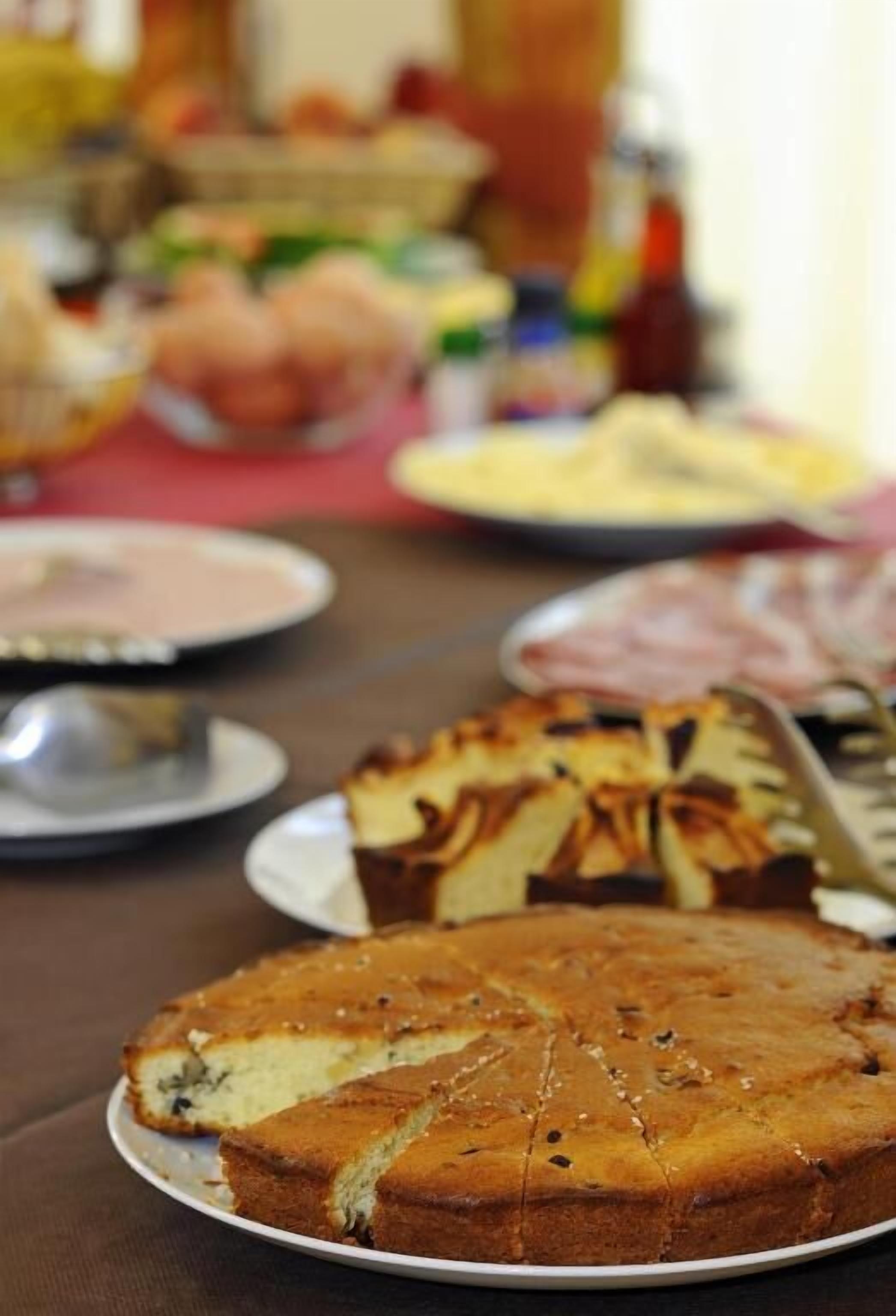 Una mesa con diversos platos, incluyendo una tarta con corteza entrelazada y un plato con carne en rodajas.