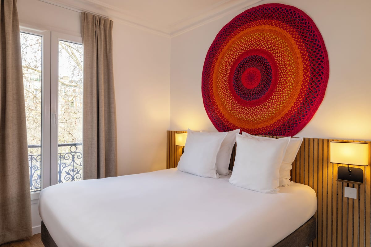 Ein Hotelzimmer mit einem großen Bett, zwei Nachttischlampen und einem an der Wand hängenden Kunstwerk.