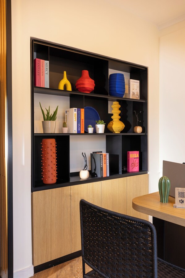 Una habitación moderna con un armario de madera, una estantería negra y una mesa redonda con una silla.