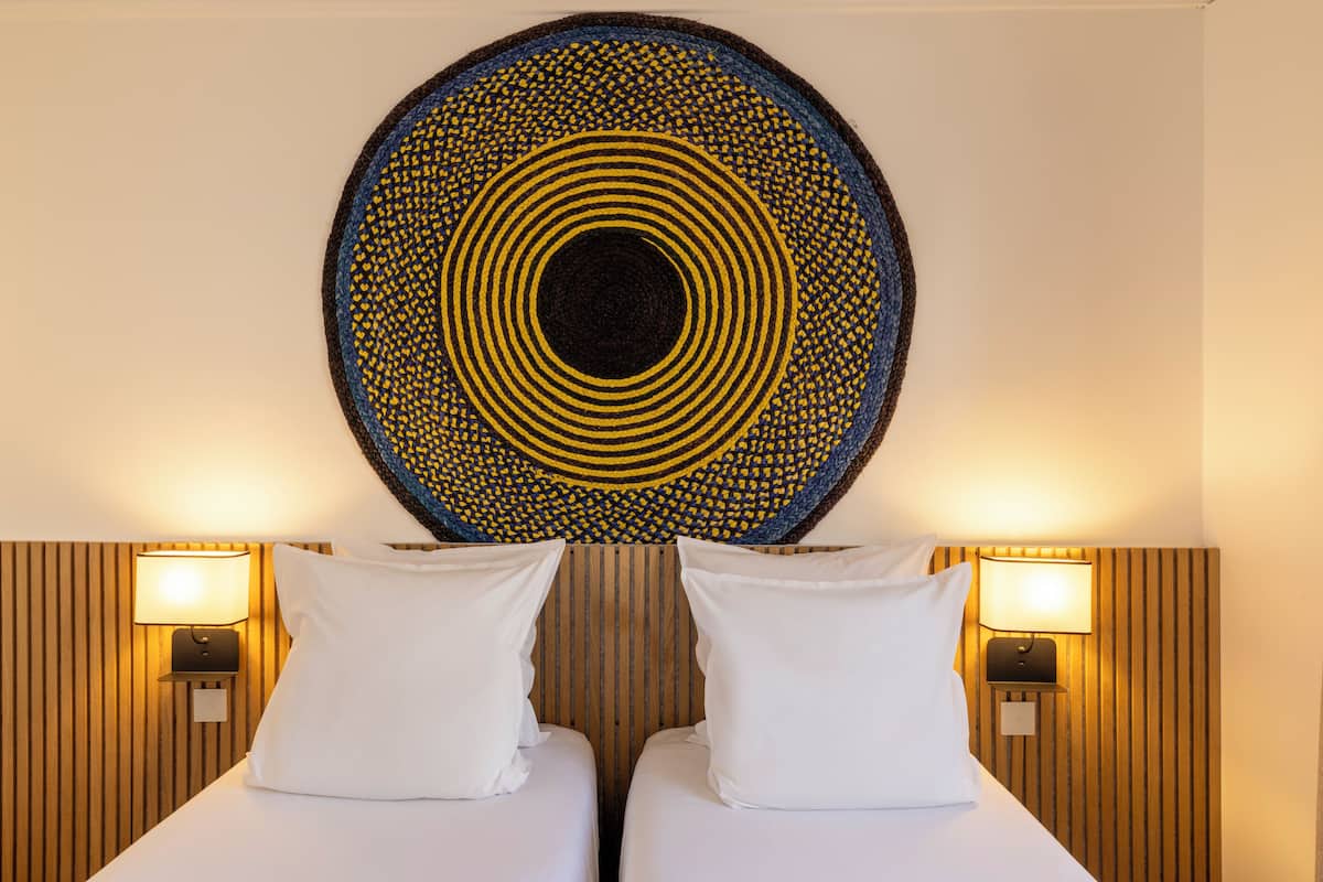 Ein Hotelzimmer mit zwei Betten, einem runden Wandbehang und zwei Wandlampen.