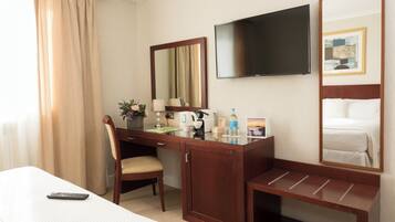 A hotel room with a bed, a desk with a chair, a TV, and a mirror.