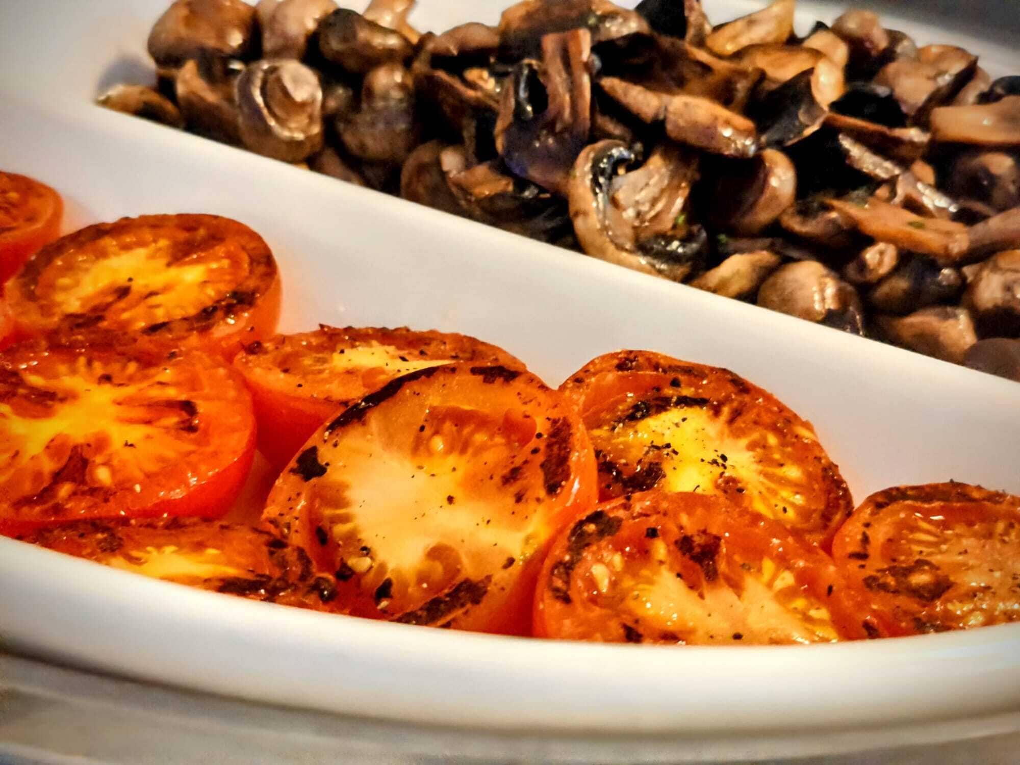 Un piatto bianco con fette di pomodori e funghi.