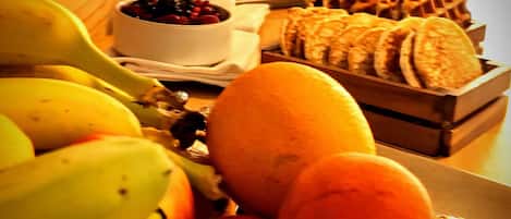 Una mesa de desayuno con frutas, gofres y una taza de café.
