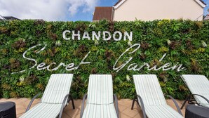 A wall with the words "CHANDON Secret Garden" and three striped lounge chairs. - The Savoy Jersey (St. Helier)