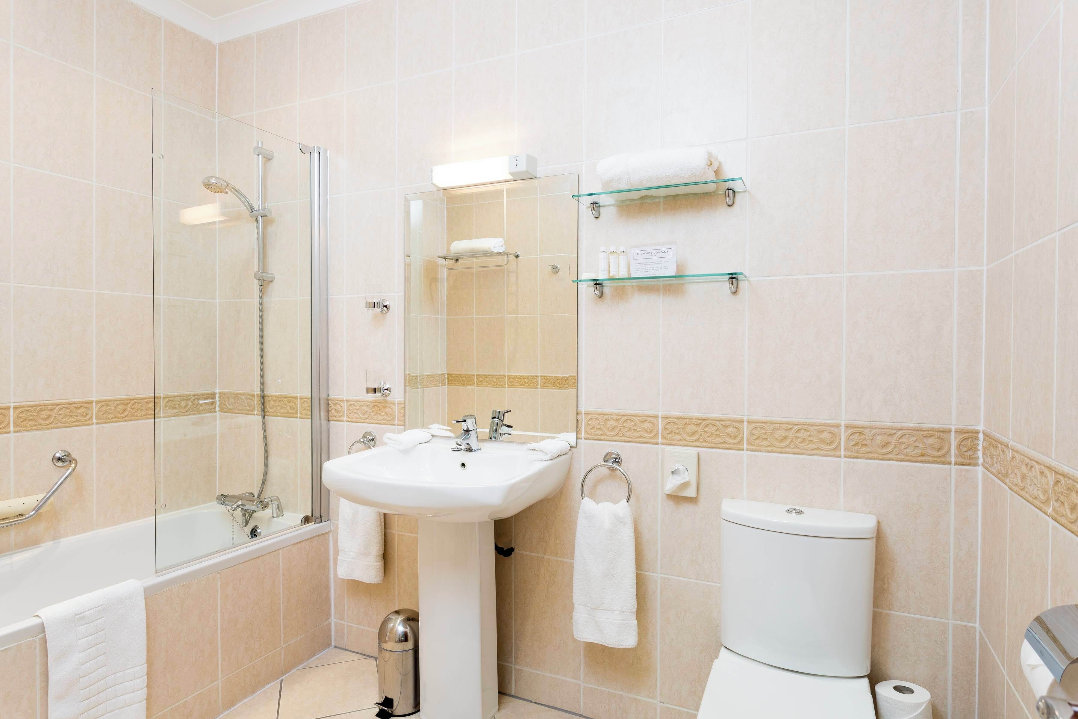 A bathroom with a bathtub, sink, toilet, and glass shower enclosure.