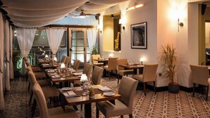 A restaurant with long tables, chairs, and a patterned floor. - The Savoy Jersey (St. Helier)