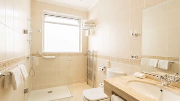 A modern bathroom with a shower, toilet, sink, and a large mirror.