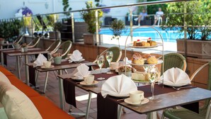 A terrace with outdoor seating, a pool, and a buffet table with food and drinks. - The Savoy Jersey (St. Helier)