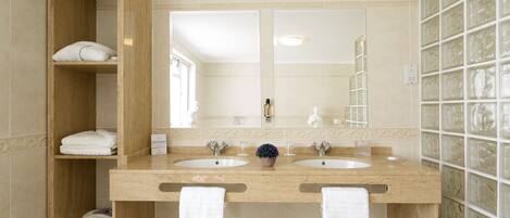 A bathroom with two sinks, a large mirror, and a wooden shelf with towels.