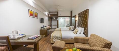 A hotel room with a bed, a sitting area with a table and chairs, a television, and a fruit bowl.
